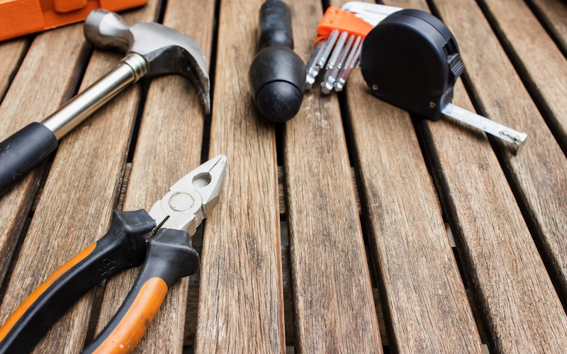 Hammer, pliers, hex keys and a tape measure on a wooden surface